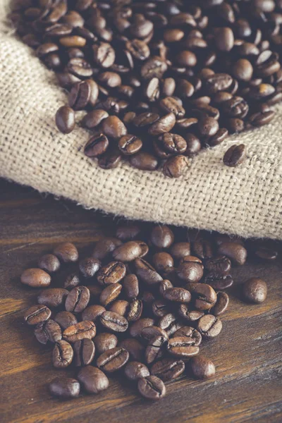 Kahve çekirdekleri çuval bezi kumaş ve ahşap arka plan