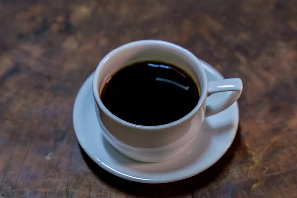 Café negro en una taza blanca puesto en una vieja mesa de madera —  Fotos de Stock