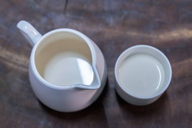 Taze süt üzerinde eski bir ahşap masa yerleştirilen bir beyaz cam yerleştirilir.