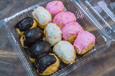 Donut ahşap bir masa üzerinde şeffaf plastik bir kutu içinde yerleştirilir.