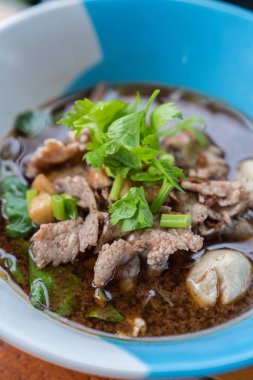 Ahşap bir masa üzerinde bir kase erişte topları vardır.