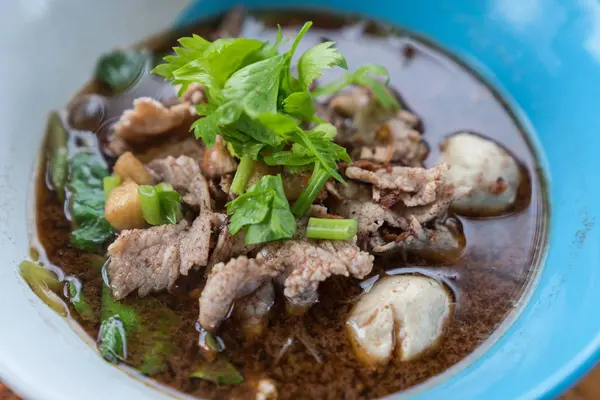 Ahşap bir masa üzerinde bir kase erişte topları vardır.