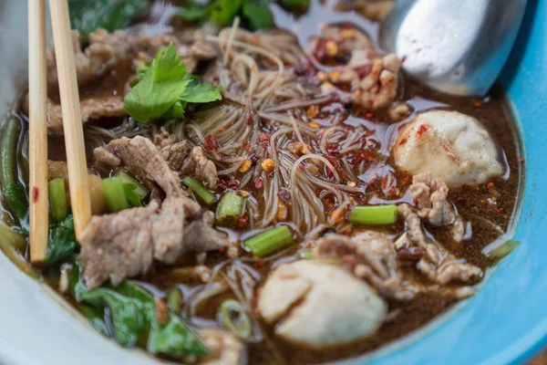 Ahşap bir masa üzerinde bir kase erişte topları vardır.