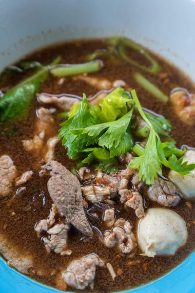 Ahşap bir masa üzerinde bir kase erişte topları vardır.