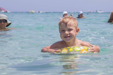 Dalgalar halinde denizde güneşli bir günde oynayan küçük çocuk