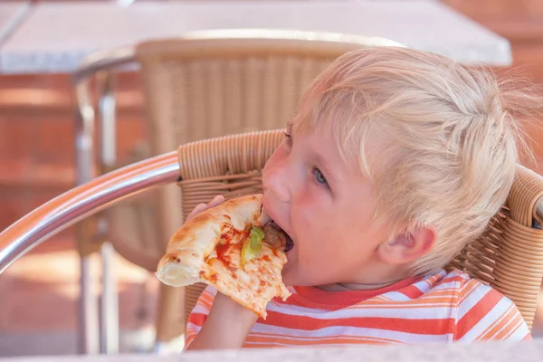 Niño come pizza en la cafetería, foto teñida . — Foto de Stock