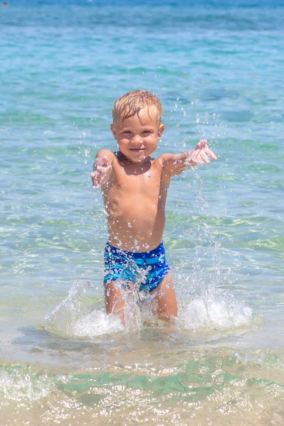 Menino brincando nas ondas no mar em um dia ensolarado — Fotografia de Stock