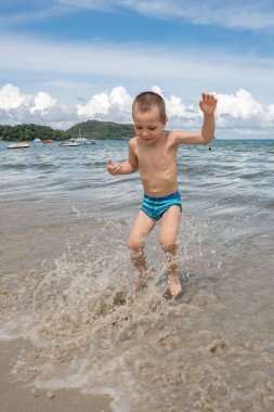 Dalgalar halinde denizde güneşli bir günde oynayan küçük çocuk