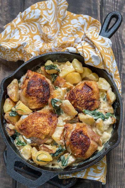 Жареная курица, картофель и шпинат со сливочным соусом в сковородке — стоковое фото