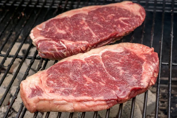 Raw beef steaks on a grill — Stock Photo, Image