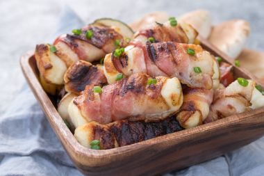 Grilled bacon wrapped haloumi with vegetables and pita clipart