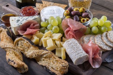 Peynir tabağı servis üzüm, reçel, prosciutto, ahşap arka plan üzerinde kraker ile