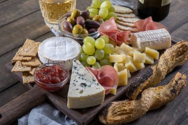 Peynir tabağı servis üzüm, reçel, prosciutto, ahşap arka plan üzerinde kraker ile