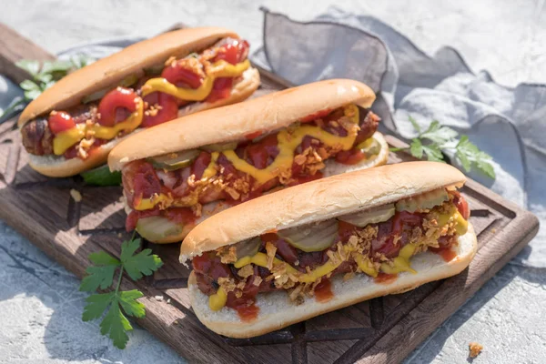 Hot Dog s slanina, klobása, kečup, hořčice žlutá, smažené cibule a okurky — Stock fotografie