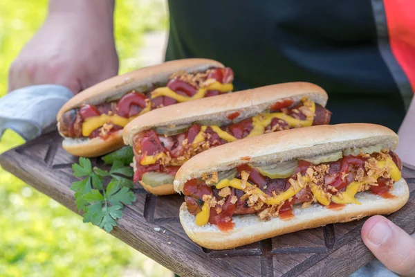 Varmkorv med bacon lindade korv, ketchup, gul senap, stekt lök och pickles — Stockfoto
