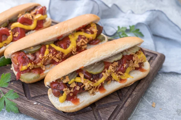 Hot Dog cu cârnați împachetați cu slănină, ketchup, muștar galben, ceapă prăjită și murături — Fotografie, imagine de stoc