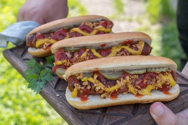 Varmkorv med bacon lindade korv, ketchup, gul senap, stekt lök och pickles — Stockfoto