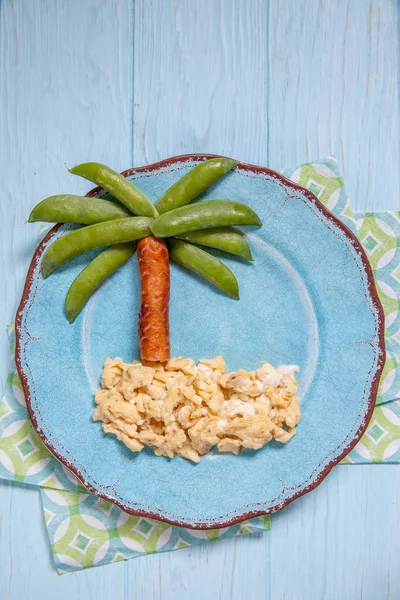 Fun food for kids - peas and sausage palm on a scrambled eggs island — Stock Photo, Image