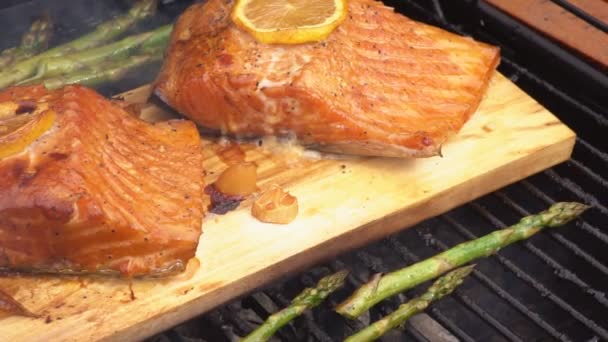 Cedar plank salmon with lemon cooking on grill — Stock Video