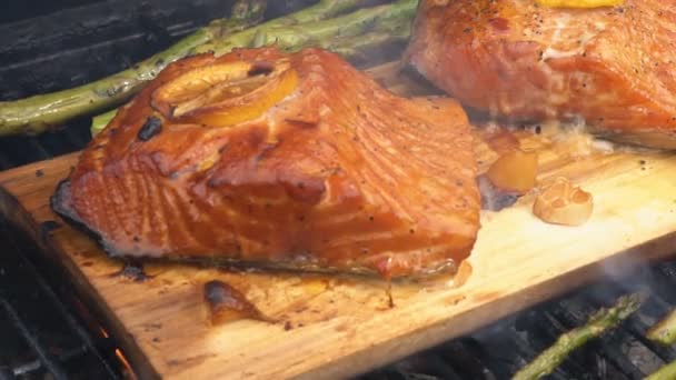 Cedar plank salmon with lemon cooking on grill — Stock Video