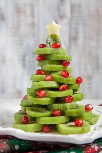 Healthy dessert idea for kids party - funny edible kiwi pomegranate Christmas tree — Stock Photo, Image