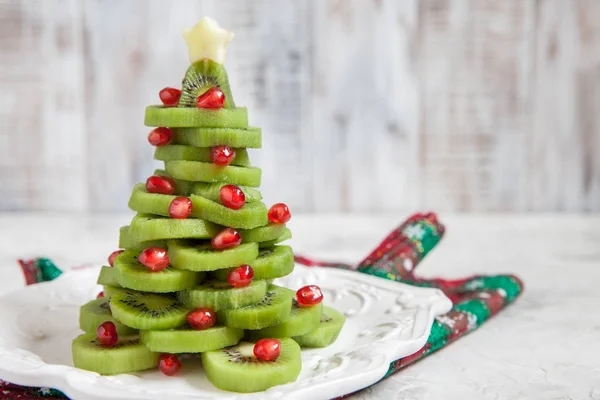 Healthy dessert idea for kids party - funny edible kiwi pomegranate Christmas tree — Stock Photo, Image