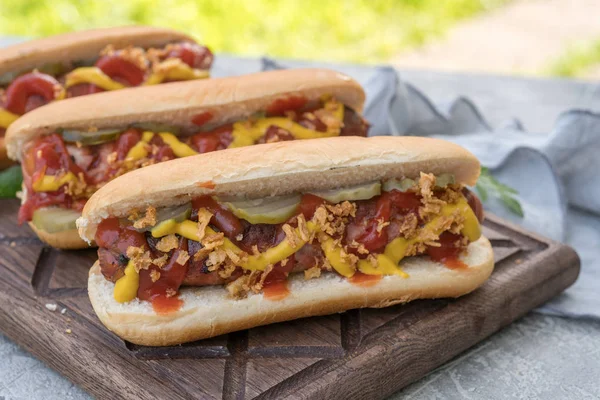 Hot Dog con salchicha envuelta en tocino, ketchup, mostaza amarilla, cebolla frita y pepinillos —  Fotos de Stock