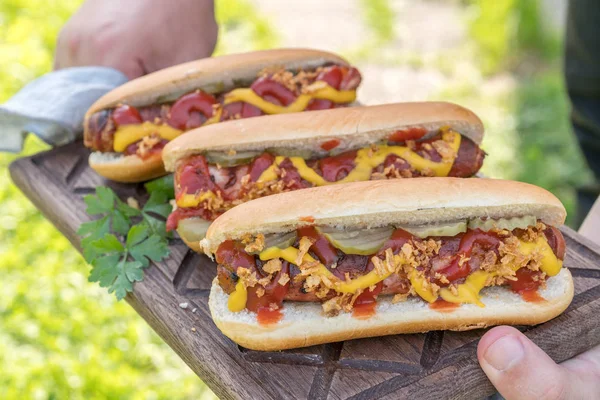 Varmkorv med bacon lindade korv, ketchup, gul senap, stekt lök och pickles — Stockfoto