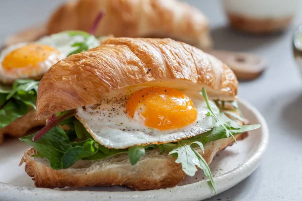 Ontbijt met Croissant broodjes met gebakken ei, salade verlaat en avocado — Stockfoto
