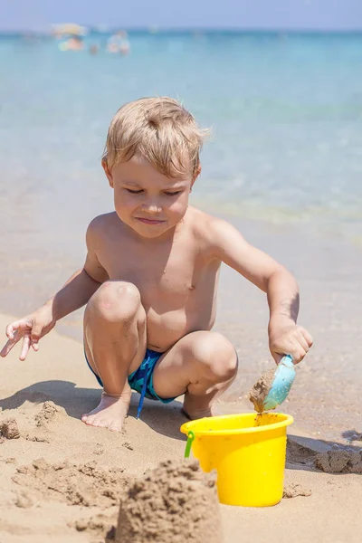 Menino brincando na areia e ondas na praia — Fotografia de Stock