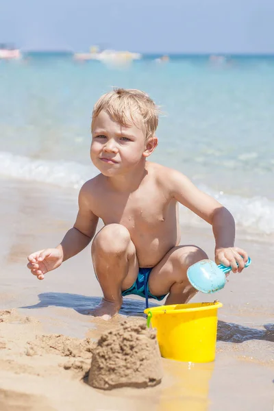 Menino brincando na areia e ondas na praia — Fotografia de Stock