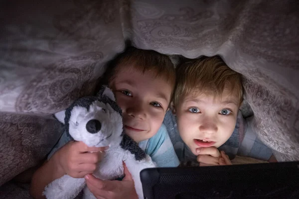 Bröder barn med surfplatta dator under filt — Stockfoto