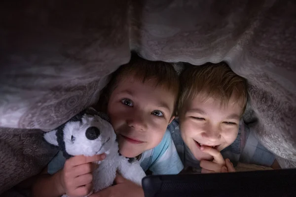 Brothers kids with tablet computer under blanket — 스톡 사진