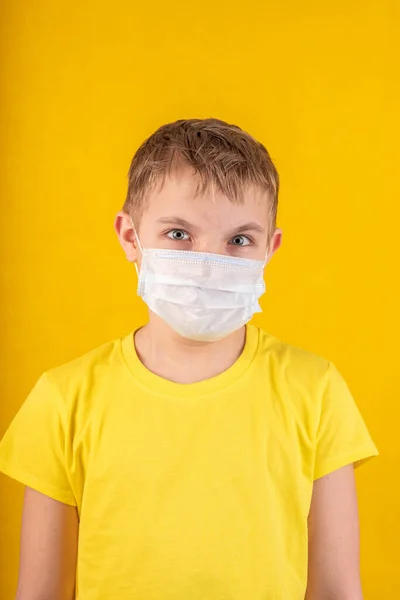 Menino bonito em máscara protetora em um fundo amarelo — Fotografia de Stock