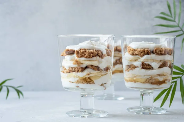 Banana caramel parfait desserts with fresh whipped cream and chocolate cookie crumbles — Stock Photo, Image