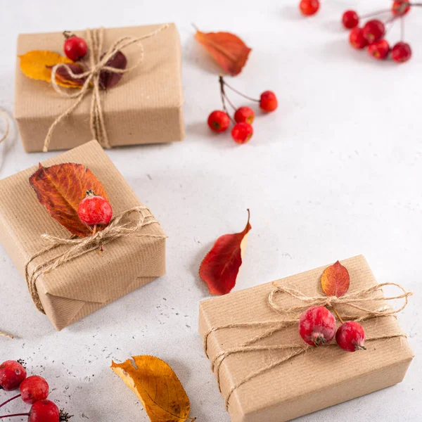 Autumn gifts with fallen leaves. Presents for Thanksgiving day wrapped in craft paper in rustic style with natural materials. Cozy autumn, copy space