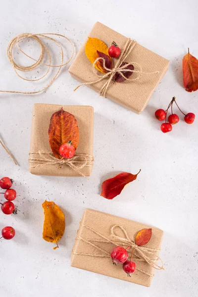 Autumn vibes, thanksgiving day presents, seasonal sale concept. Fall composition with presents in craft paper decorated with dried leaves on white background. Top view