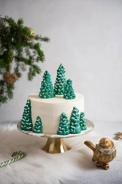 Winter cake. Christmas cake decorated with spruces on golden stand on gray background. Festive christmas, New Year table. Confectionery, bakery concept. Copy space.