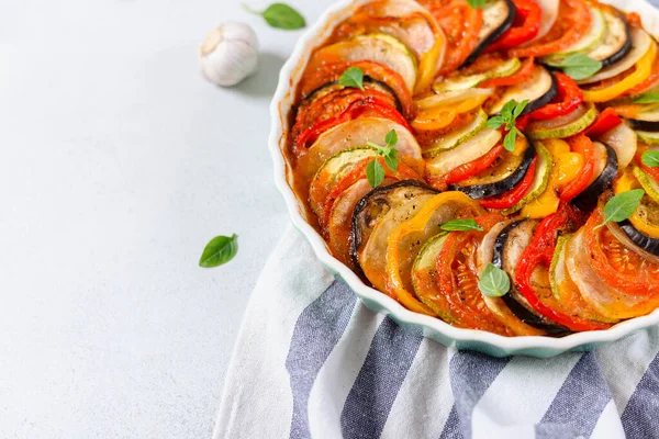 Ratatouille in baking dish on white background. Traditional French Provencal vegetable dish. Dieting, vegan food. Ratatouille casserole. For menu or banner. Side view, copy space for text