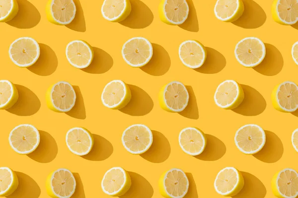 Food pattern of fresh lemons in a cut on yellow background. Composition from citrus fruits, top view, flat lay.