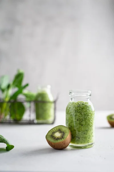 Healthy green smoothie with spinach, kiwi and green apple in a glass bottle on a light background. Healthy lifestyle, detox, dieting, fitness menu. Side view, copy space for text.