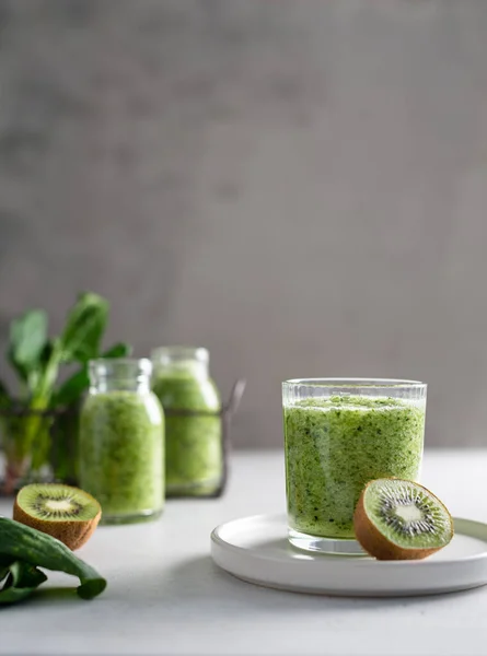Healthy green smoothie with spinach, kiwi and green apple in a glass on a light background. Healthy lifestyle, detox, dieting, fitness menu. Side view, copy space for text.