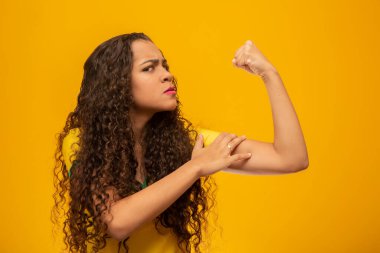Kıvırcık saçlı, Brezilyalı güzel bir destekçi. Brezilyalı futbol taraftarı. Brezilyalı spor hayranı. Sarı arkaplanda.