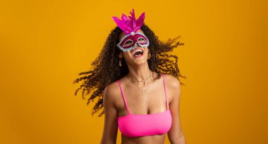 Karnaval gecesi için giyinmiş güzel bir kadın. Renkli maskesiyle karnavalın tadını çıkarmaya hazır gülümseyen kadın. Yukarıya işaret ediliyor.