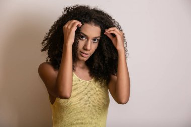 Kıvırcık saçlı, kameraya bakıp gülümseyen genç Afro-Amerikalı kadın. Kıvırcık saçlı, kameraya bakıp gülümseyen tatlı afro kız..