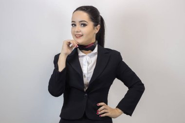 Beyaz arka planda yalnız poz veren şık kostümlü sevimli hostes.