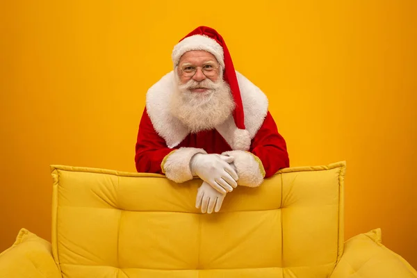 Papai Noel Sentado Sofá Amarelo Fundo Amarelo Com Espaço Cópia — Fotografia de Stock