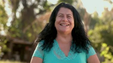 Bahçede poz veren gülümseyen olgun kadın.