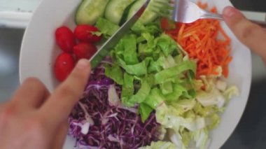 Çatal ve bıçakla sağlıklı salata yiyen kişi.