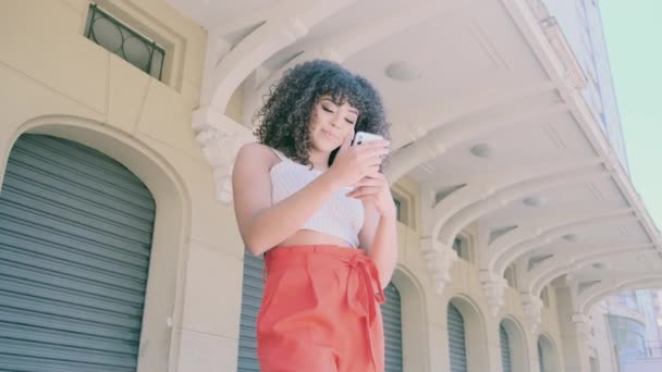 Elegante Mujer Rizada Usando Teléfono Inteligente Posando Fondo Ciudad — Vídeo de stock